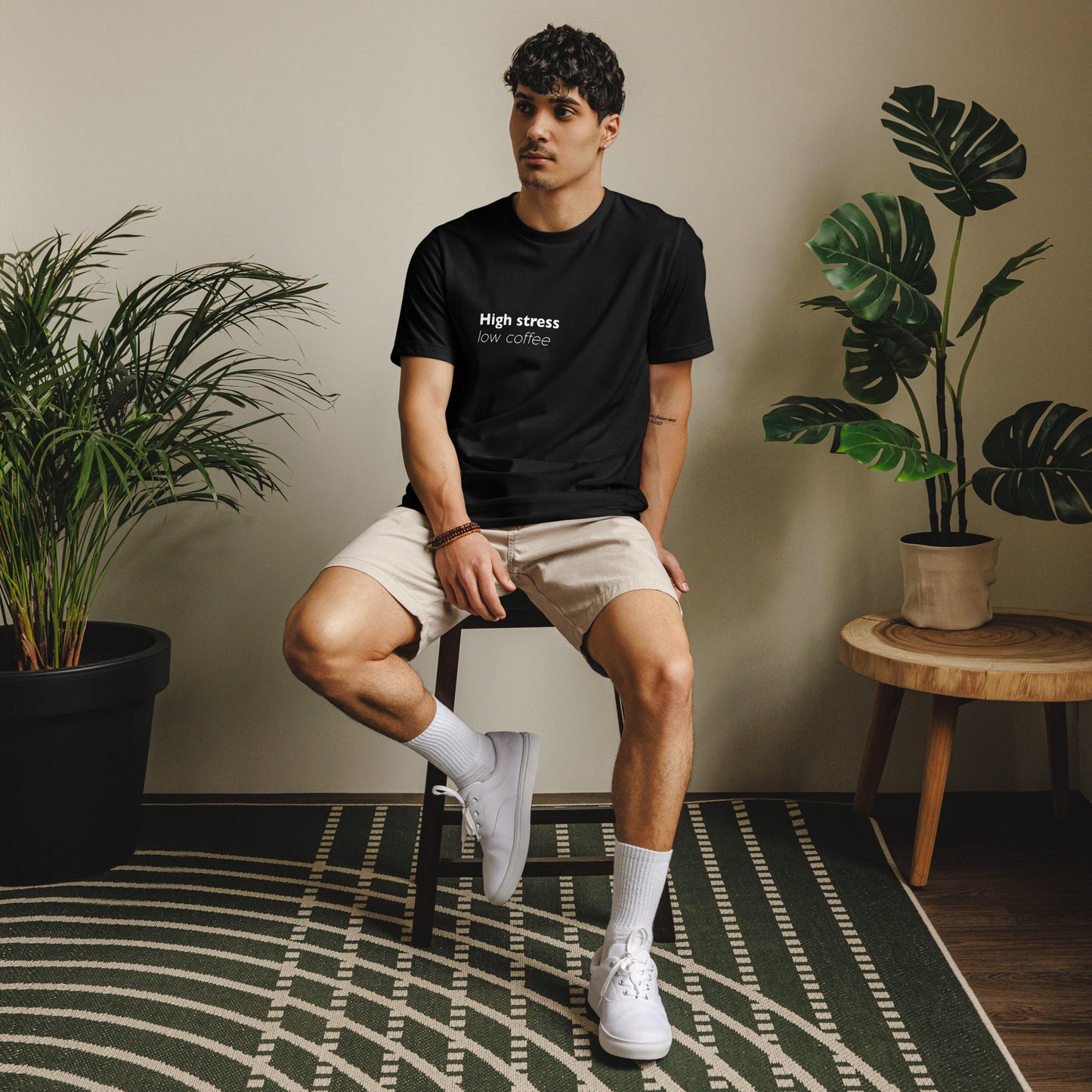 Black unisex eco t-shirt featuring "High Stress Low Coffee" design by Knot Qualified, front view.